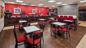 um restaurante com paredes e mesas vermelhas e cadeiras vermelhas em Chicago Southland Hotel em Oak Forest