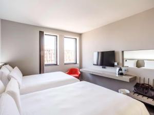 a hotel room with two beds and a flat screen tv at Pullman Toulouse Centre Ramblas in Toulouse