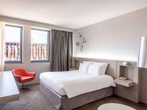 a hotel room with a bed and a red chair at Pullman Toulouse Centre Ramblas in Toulouse