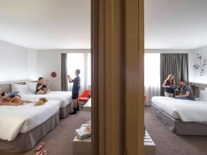 - un groupe de personnes assises sur les lits d'une chambre d'hôtel dans l'établissement Pullman Toulouse Centre Ramblas, à Toulouse