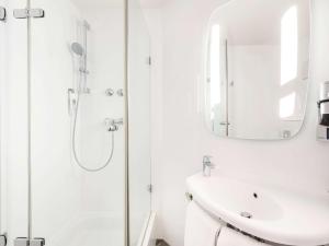 a white bathroom with a sink and a mirror at ibis Hotel München City in Munich