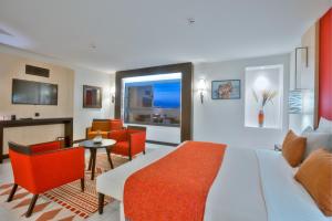 Habitación de hotel con cama, mesa y sillas en Azalaï Hôtel Bamako, en Bamako