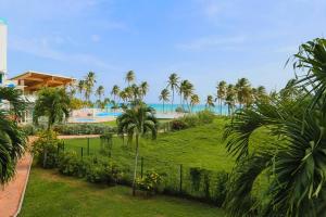 Blick auf ein Resort mit Palmen und das Meer in der Unterkunft AZUR - Séjour FARNIENTE en Guadeloupe! in Le Gosier