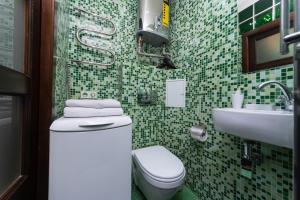Baño de azulejos verdes con aseo y lavamanos en Apartments on Besarabka en Kiev