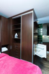 1 dormitorio con cama rosa y armarios de madera en Apartments on Besarabka, en Kiev