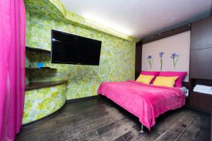 a bedroom with a pink and yellow bed with a flat screen tv at Apartments on Besarabka in Kyiv