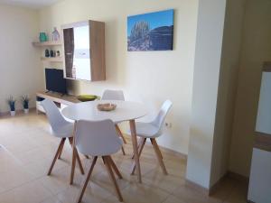 una sala da pranzo con tavolo bianco e sedie bianche di Laderas del Palmar a Palm-Mar