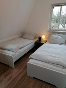 2 Betten in einem weißen Zimmer mit Fenster in der Unterkunft Ferienhaus Bremke am Alfsee in Rieste