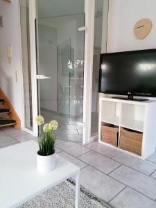 ein Wohnzimmer mit einem TV und einem weißen Tisch in der Unterkunft Ferienhaus Bremke am Alfsee in Rieste