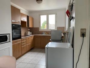 a kitchen with wooden cabinets and a white refrigerator at F3 - Séjour Paris + Disneyland - 37bd Segrais Lognes in Lognes