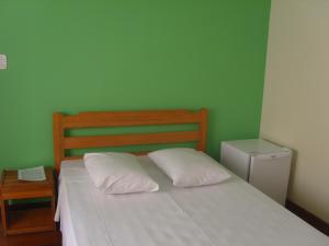 a green bedroom with a bed with two white pillows at Hotel Modelo in Poços de Caldas