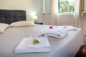 a white bed with towels and flowers on it at Villa RAXI in Plátanos