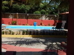 a swimming pool with two chairs next to a fence at Casas Barra Sol in Barra Grande