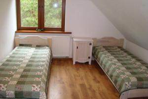 two beds in a room with two windows at Dom pod Dziką Gruszą in Piecki