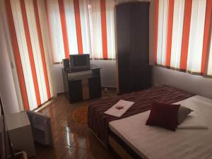 a small bedroom with a bed and a television at Vila Denis in Costinesti