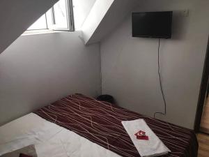 a small bedroom with a bed with a television on the wall at Vila Denis in Costinesti
