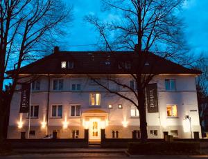 un gran edificio blanco con luces encendidas por la noche en Hotel-Cocco-Bello in der Villa Foret en Ludwigsburg