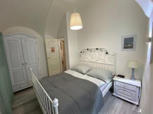 a white bedroom with a bed and a night stand at Apartmány Kováčska in Košice