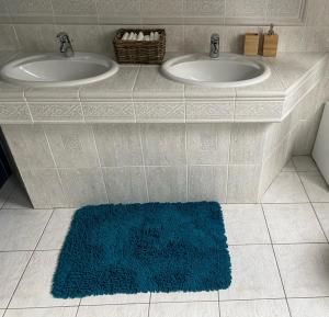 ein Badezimmer mit zwei Waschbecken und einem blauen Teppich in der Unterkunft Penzión Exclusive in Trenčín