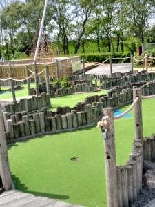 a playground with wooden fences and a putting green at lakeland leisure park in Flookburgh