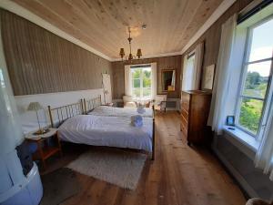 1 dormitorio con 1 cama blanca en una habitación con paredes de madera en Frägsta Hälsingegård B&B, en Näsviken