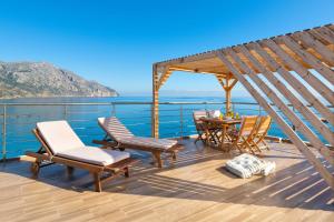 a deck with a table and chairs and the ocean at Villa Diafani, Anna in Diafani