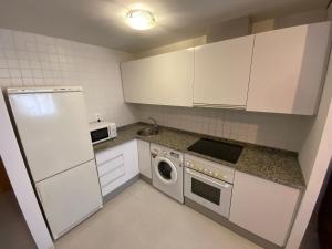uma pequena cozinha com armários brancos e uma máquina de lavar louça em Apartamento con piscina a 350 metros de la playa em Vinarós