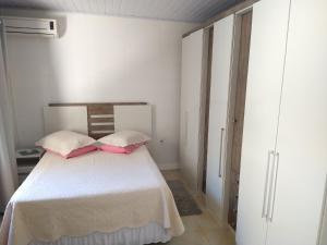 Un dormitorio con una cama con almohadas rosas. en Casa Beira Mar Mariscal 1, en Bombinhas