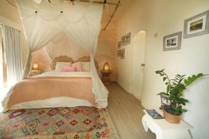 a bedroom with a canopy bed with pink pillows at The Chillhouse Canggu by BVR Bali Holiday Rentals in Canggu