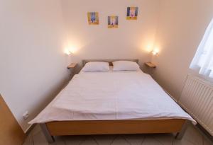 Cama en habitación pequeña con 2 lámparas en Apartmany Riviera 505 en Lipno nad Vltavou
