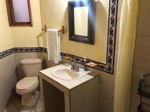 a bathroom with a toilet and a sink and a mirror at La Gloria de Los Ángeles in Tzintzuntzán