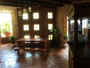 a living room with a wooden table and windows at La Gloria de Los Ángeles in Tzintzuntzán