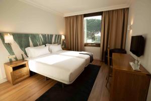 a bedroom with a large white bed and a window at Hotel Eden Park by Brava Hoteles in Riudellots de la Selva