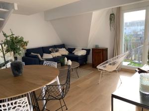 uma sala de estar com um sofá azul e uma mesa e cadeiras em LA BAULE - COUP DE CŒUR – T3 - Tout à Pied em La Baule