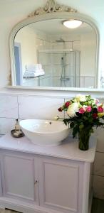 a bathroom with a sink and a vase of flowers at Maugersbury Park Suite in Stow on the Wold