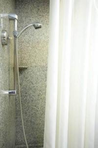 a shower stall with a white shower curtain at Majestic Suites Hotel in Bangkok