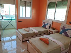 two beds in a room with two windows at Full Appart Hôtel in Kenitra