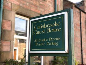 un cartel para una casa de huéspedes frente a un edificio en Carisbrooke Guest House en Inverness