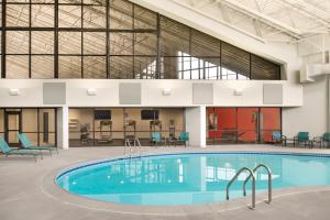uma grande piscina num edifício com cadeiras e mesas em Holiday Inn - Bloomington - Normal, an IHG Hotel em Normal