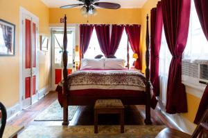 a bedroom with a bed with red curtains and a fan at The Blue60 Marigny Inn in New Orleans