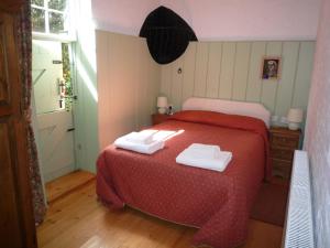 a bedroom with a red bed with two towels on it at Brackenborough Hall Coach House - Saddle Room in Louth +2 photos