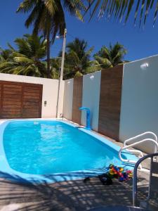 a blue swimming pool with palm trees in the background at CASA DE PRAIA NO MIAI DE CIMA, CORURIPE 90 metros da praia in Coruripe