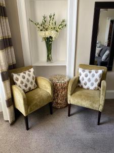 a living room with two chairs and a vase of flowers at No12 Hotel in North Berwick