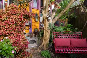 a red bench sitting under a tree in a garden at The Blue60 Marigny Inn in New Orleans