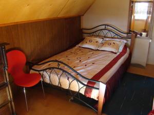 a bedroom with a bed and a red chair at Karineeme Holiday House in Mahu
