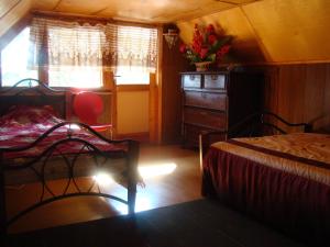 a bedroom with two beds and a dresser and a window at Karineeme Holiday House in Mahu
