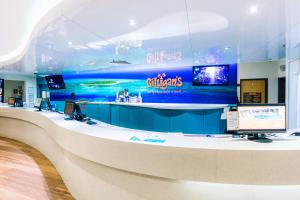 a large lobby with a reception desk and a large wall at Gilligan's Backpacker Hotel & Resort Cairns in Cairns