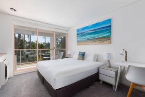 1 dormitorio con cama, escritorio y ventana en Charlesworth Bay Beach Resort, en Coffs Harbour