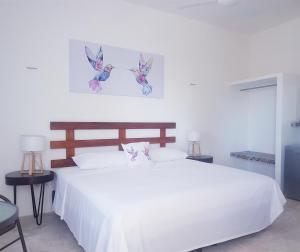 ein Schlafzimmer mit einem weißen Bett mit zwei Vögeln an der Wand in der Unterkunft Casa Chujuk by Spirit Group in Holbox