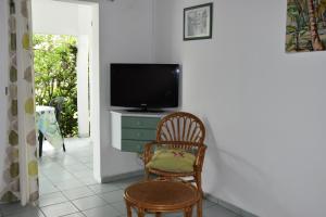 - un salon avec une chaise et une télévision dans l'établissement La Bougainvillée, à Saint-François